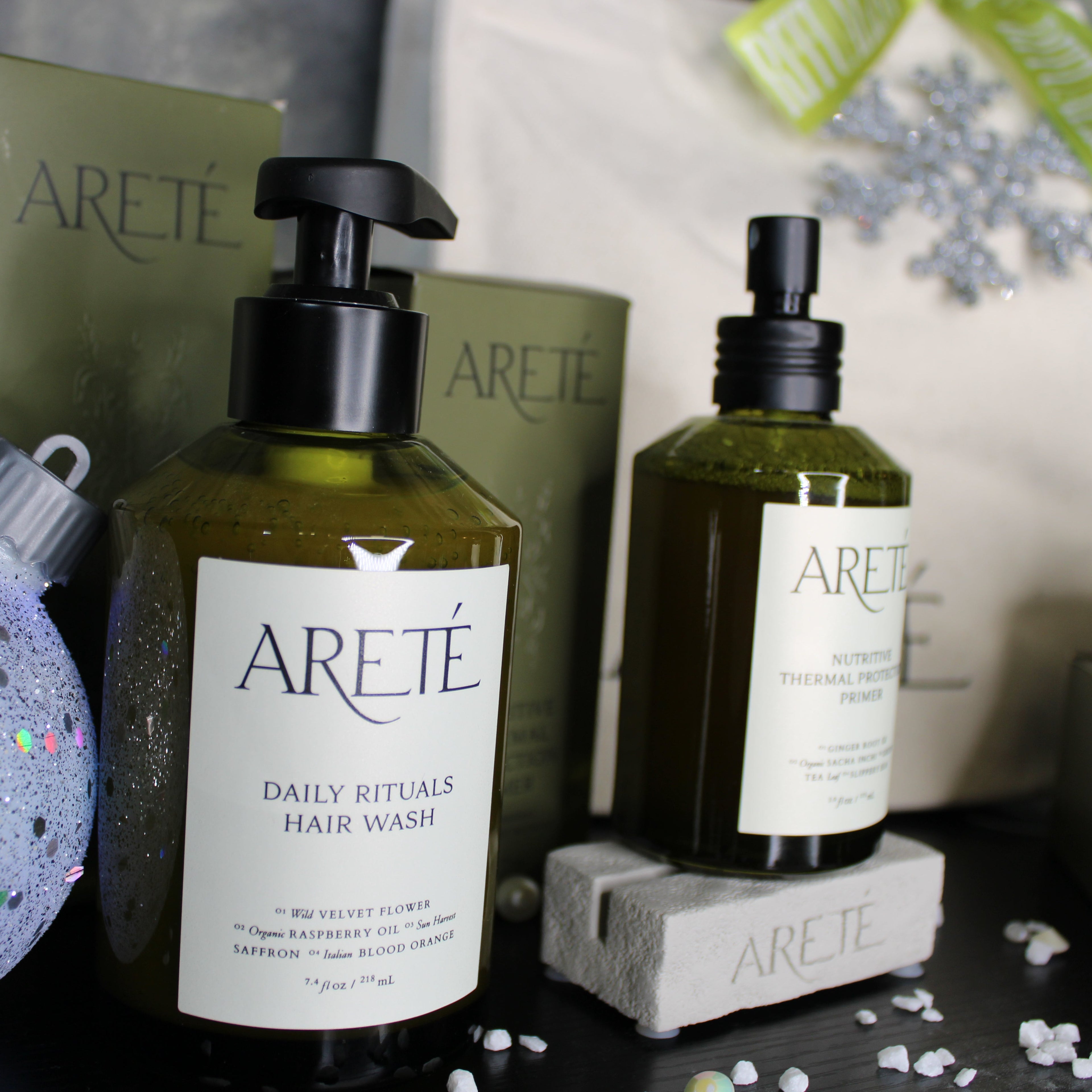 ARETE hair care products including a bottle and a pump on a dark surface with decorative elements.