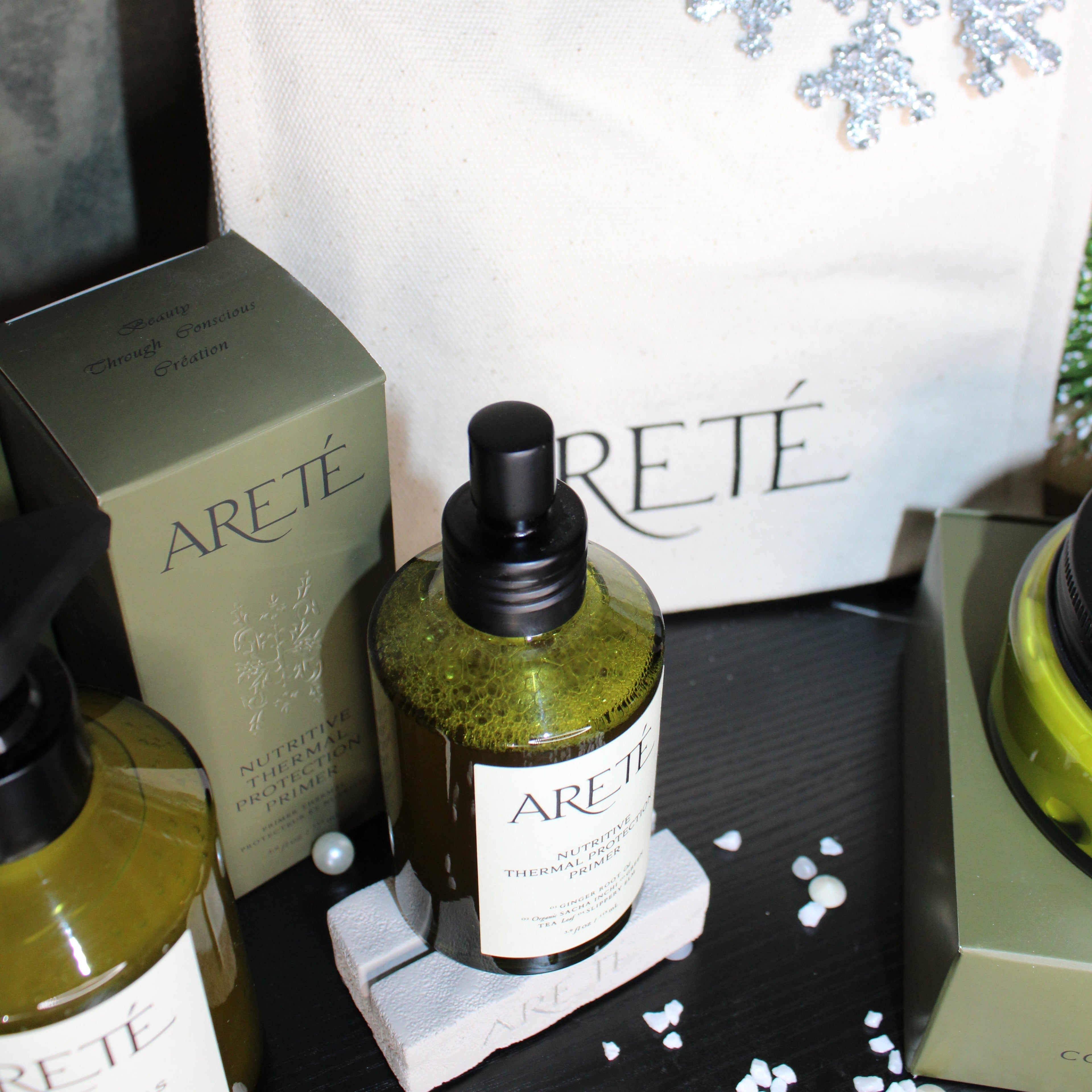 Bottle of Arete skincare product on a magazine with snowflake decorations