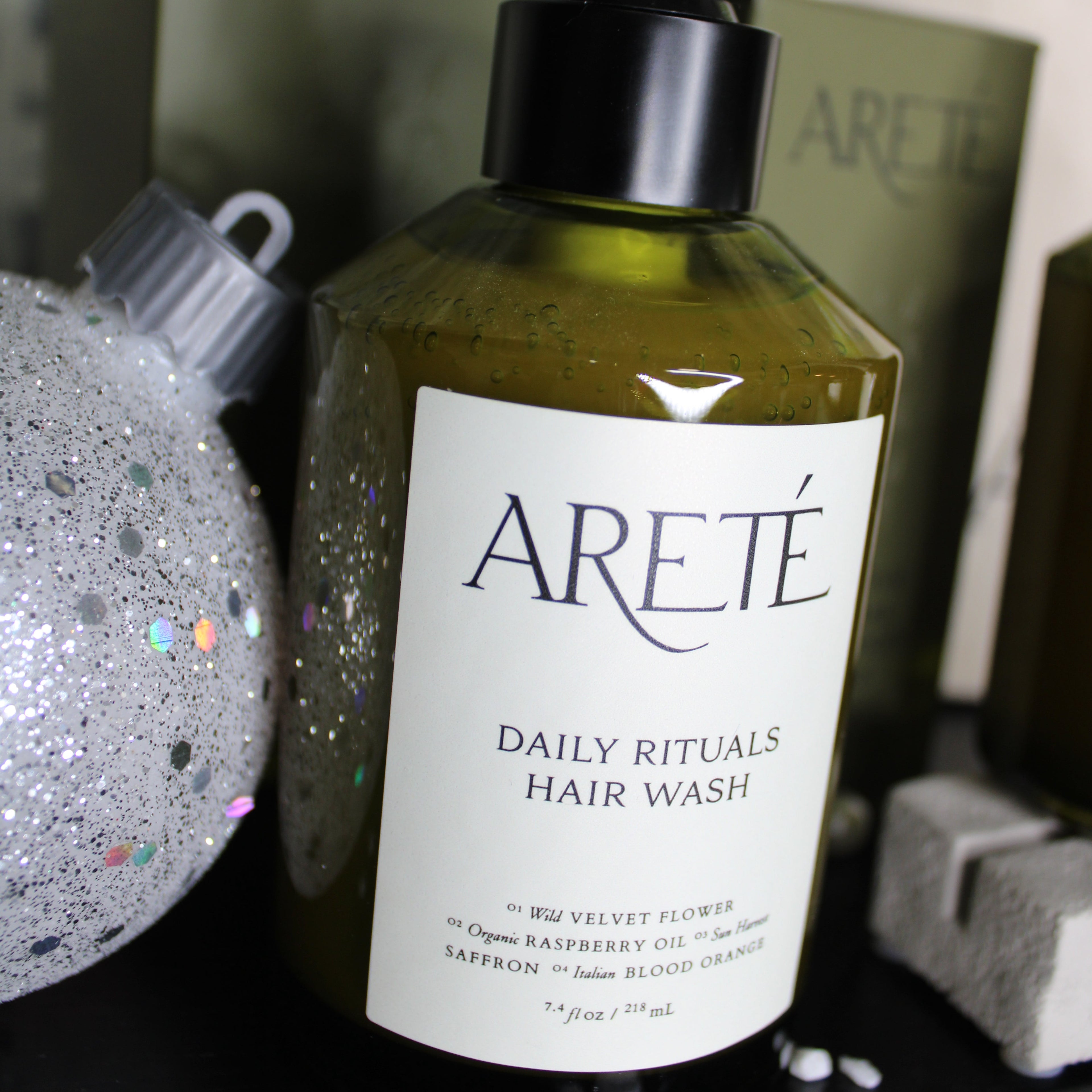 Bottle of Arete Daily Rituals Hair Wash with a label on a textured surface.