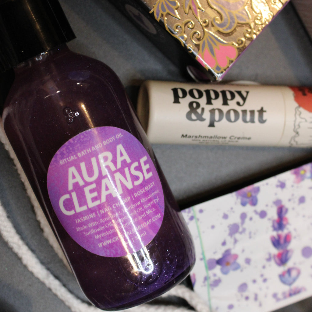 Bottle of Aura Cleanse with a purple label on a surface with other products.