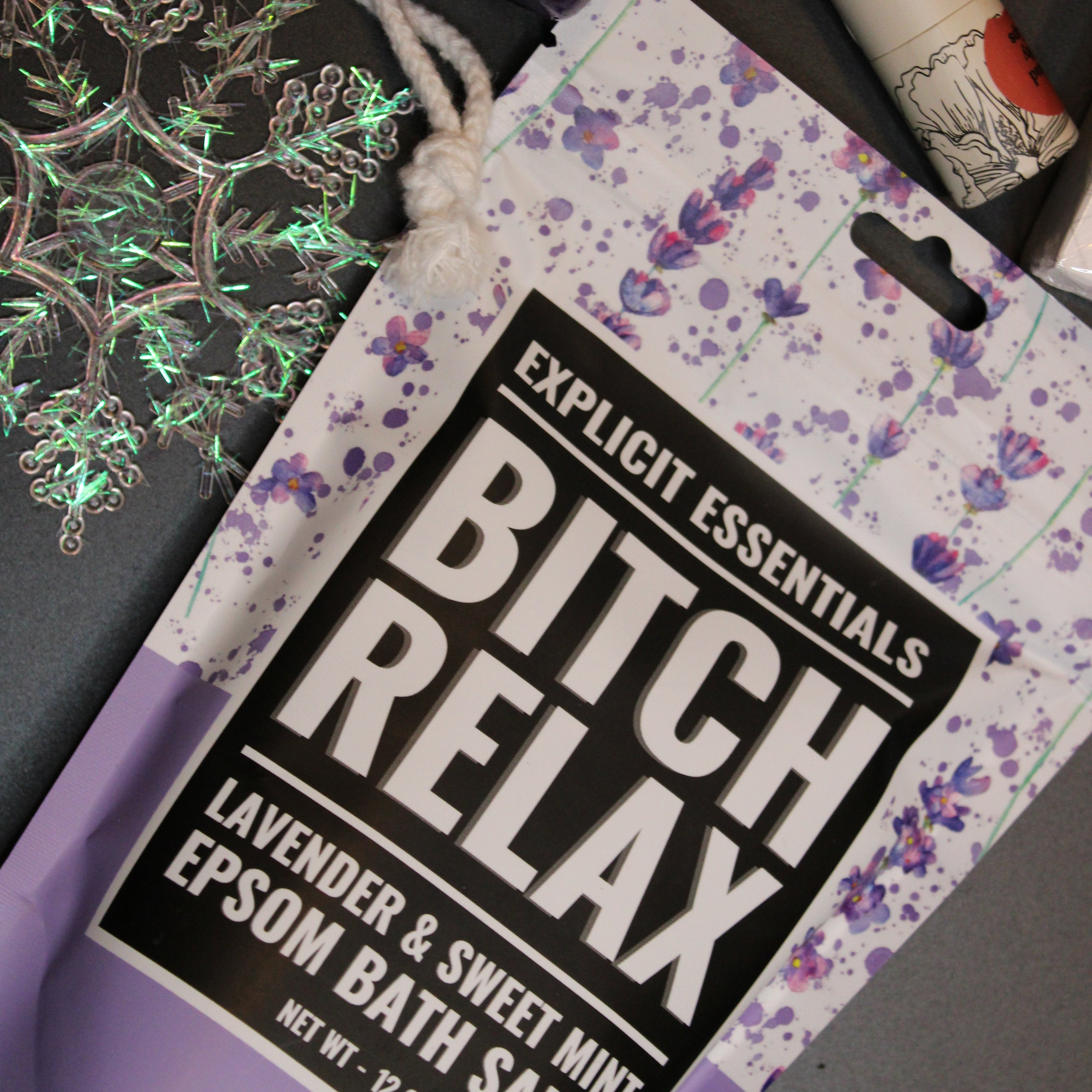 Packaging of 'Bitch Relax' bath salts with a colorful label on a dark background.