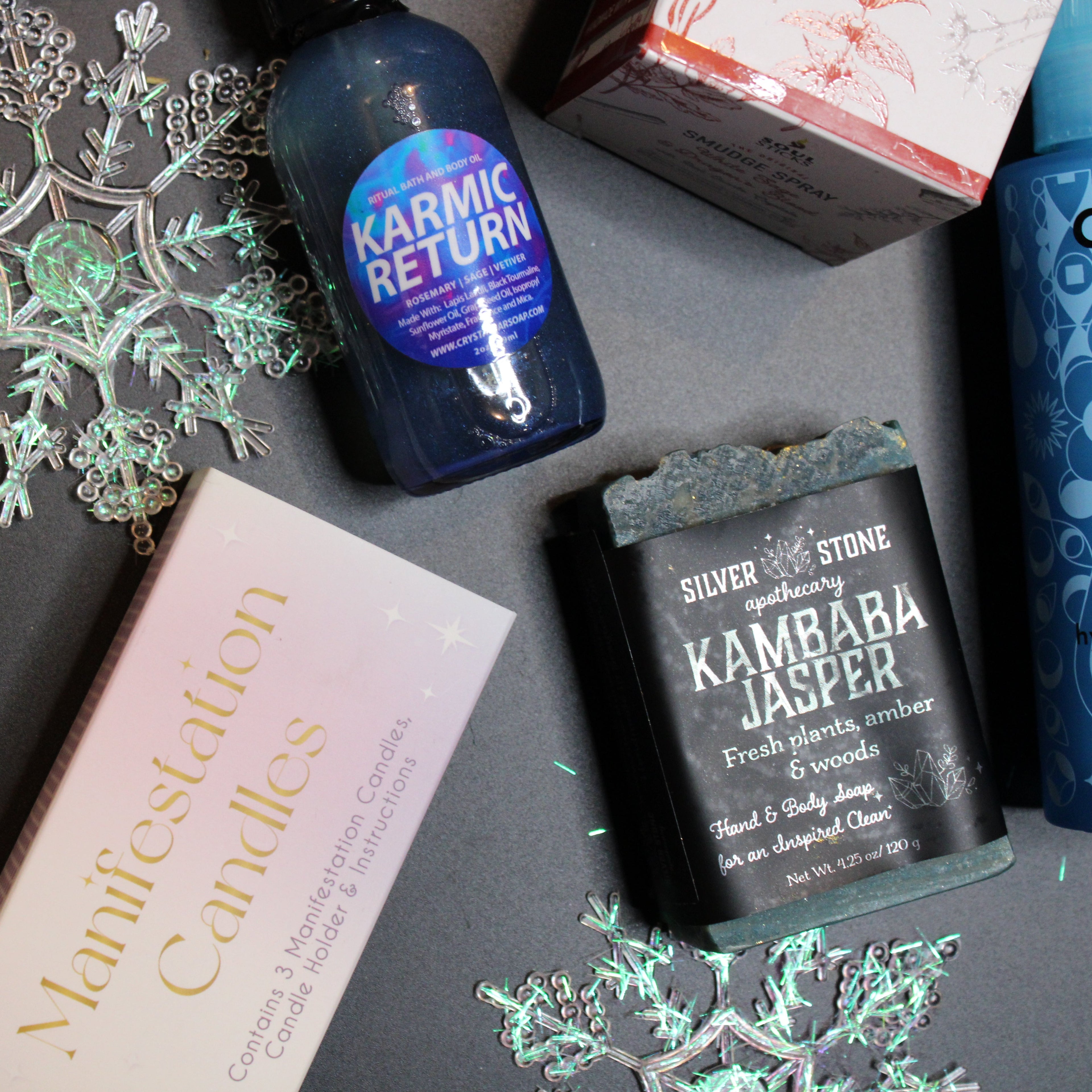 Collection of wellness products including bottles, a box, and a candle on a dark surface with decorative elements.