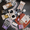 Collection of small products and packaging on a dark surface with decorative tinsel.
