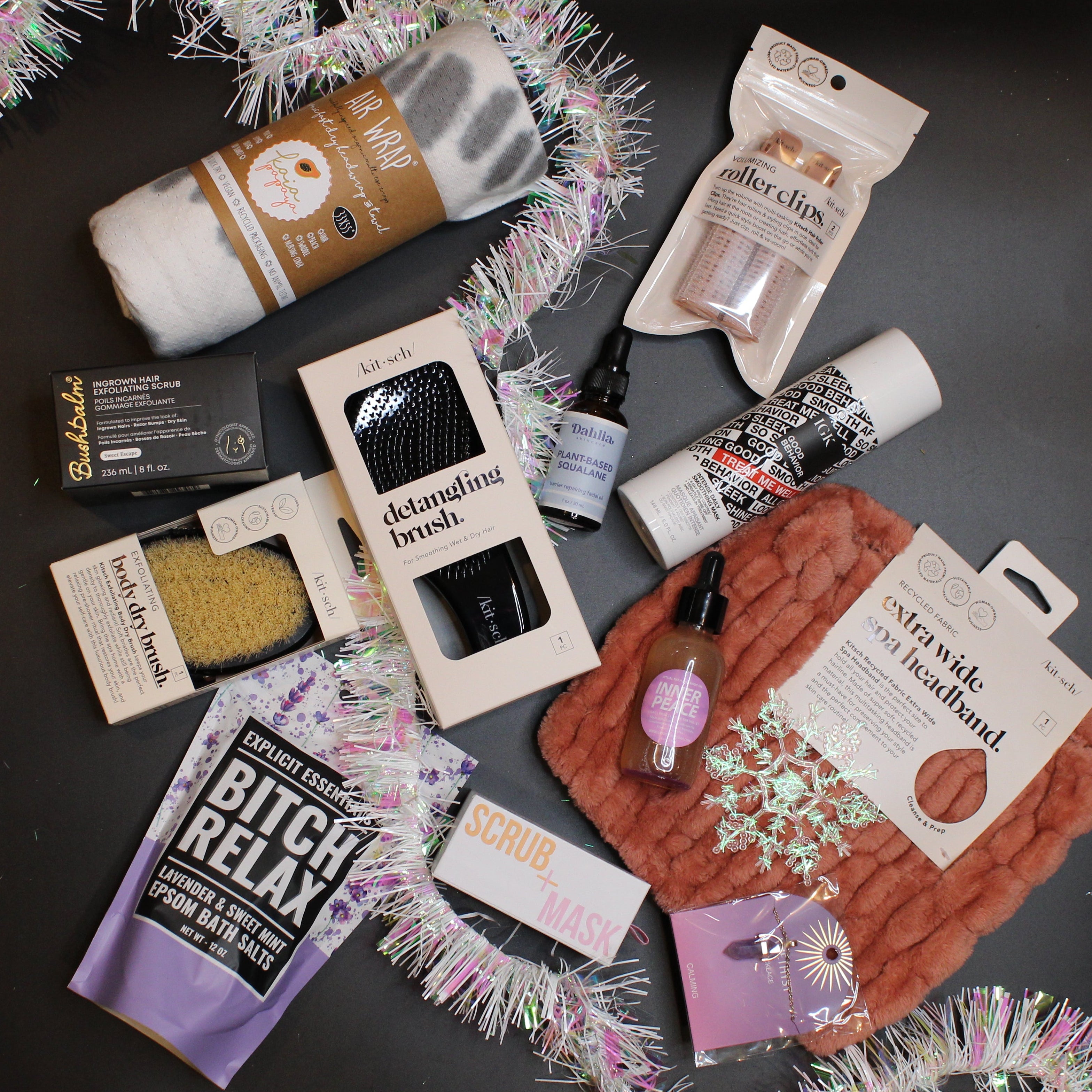 Collection of small products and packaging on a dark surface with decorative tinsel.