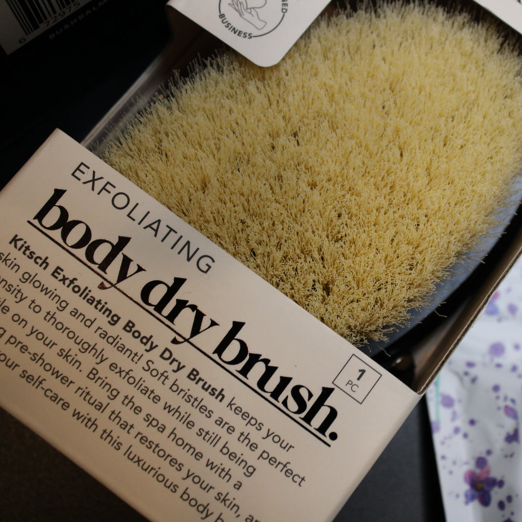 Exfoliating body dry brush in packaging with visible text and a blurred background.