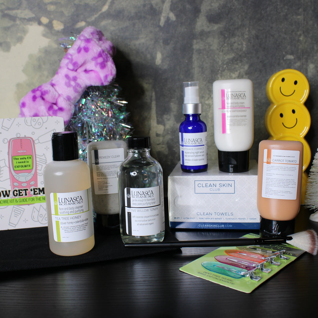 Collection of skincare products and accessories on a dark surface with a textured gray background.