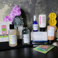 Collection of skincare products and accessories on a dark surface with a textured gray background.
