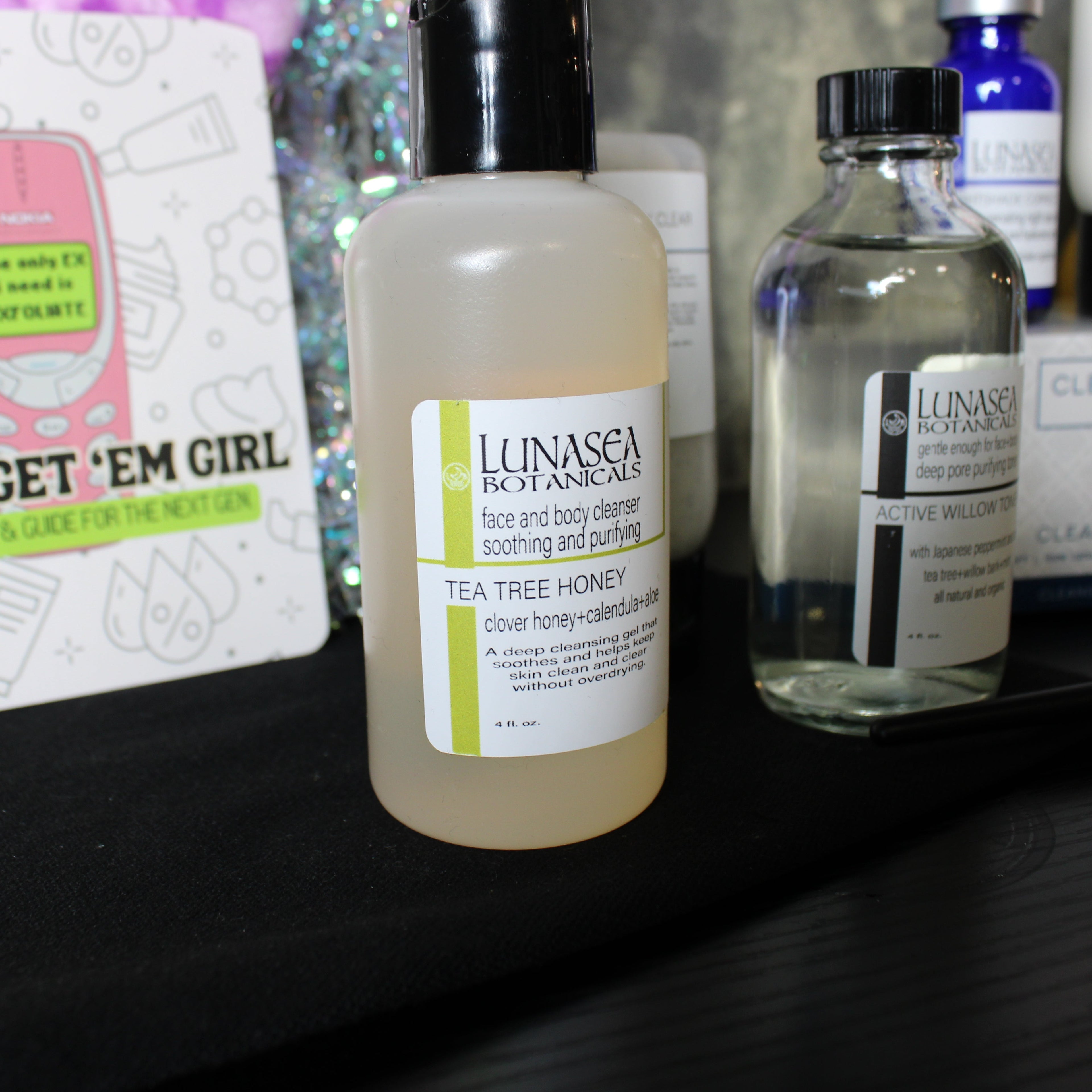 Lunasea Botanicals skincare products on a shelf with a 'Glow Get 'Em Girl' book.