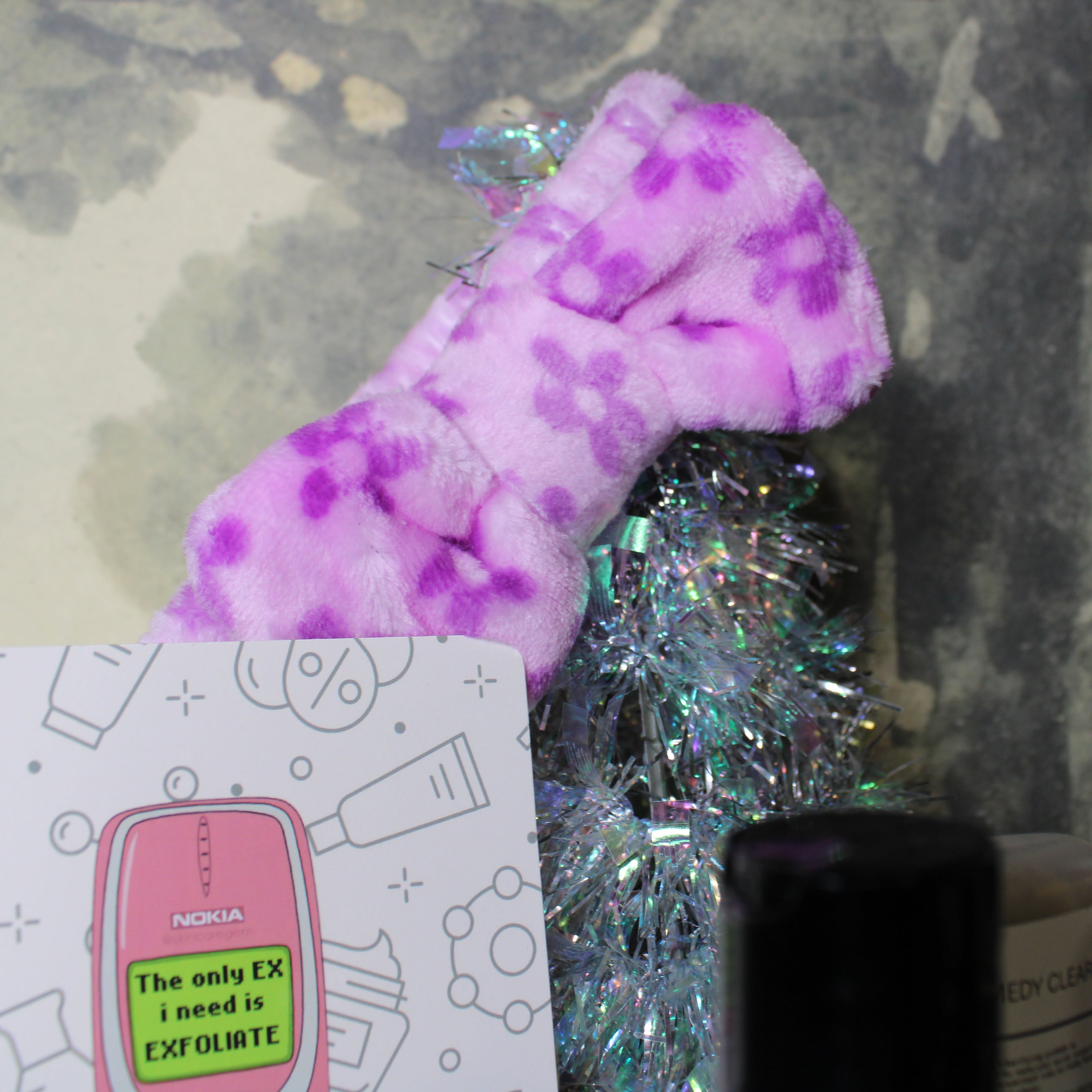 Purple fuzzy toy with floral patterns on a gray background