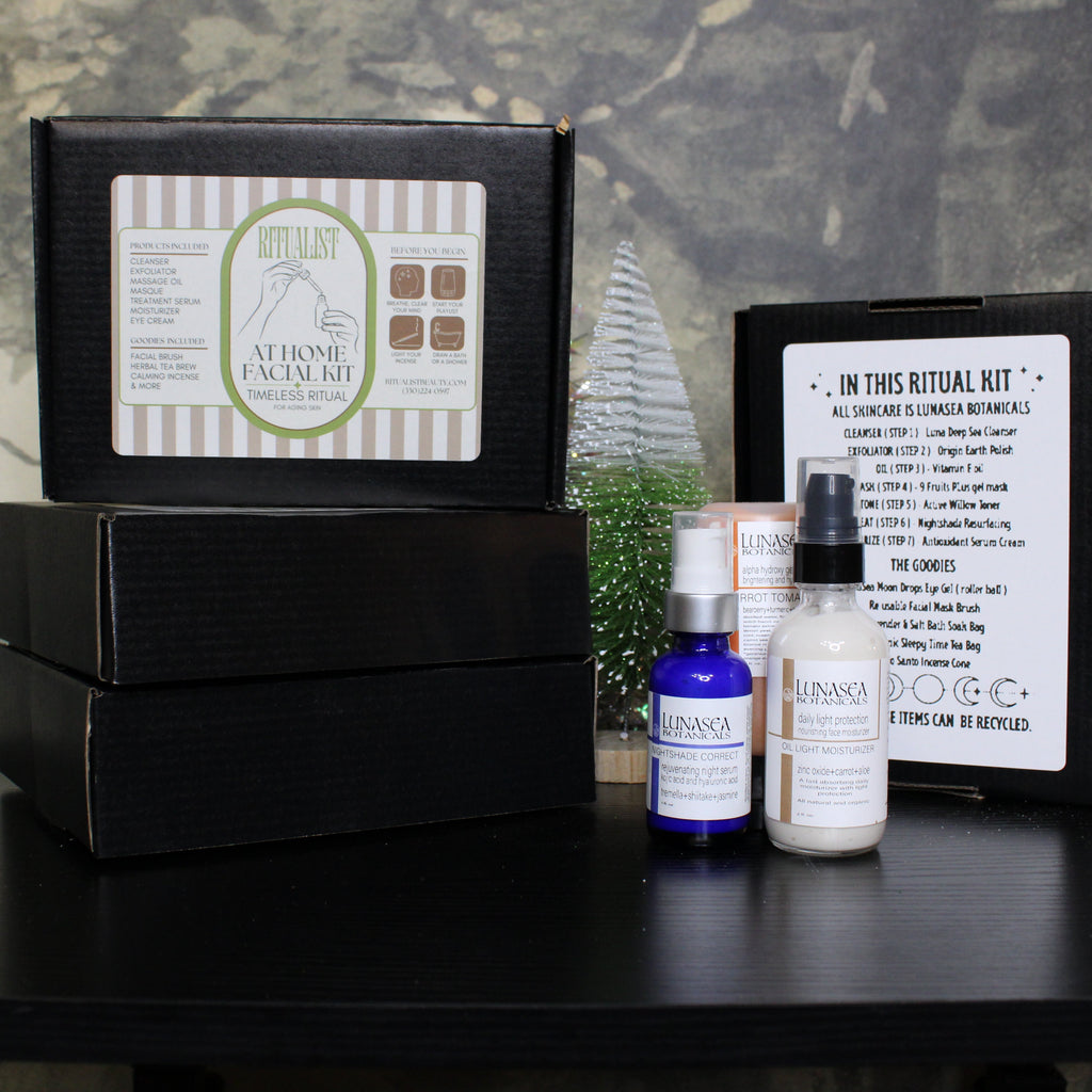 Facial kit with bottles and packaging on a dark surface with a floral background