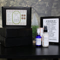 Facial kit with bottles and packaging on a dark surface with a floral background