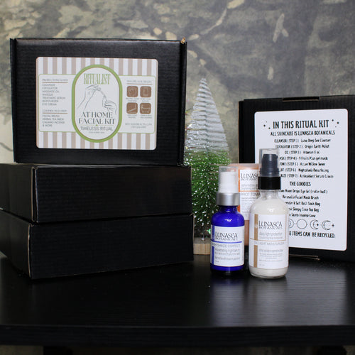 Facial kit with bottles and packaging on a dark surface with a floral background